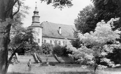 Zámek Žerotínů v Bludově se skleníkem ve 30. letech 20. století. Před skleníkem stojí zahradník Jan Marek. 